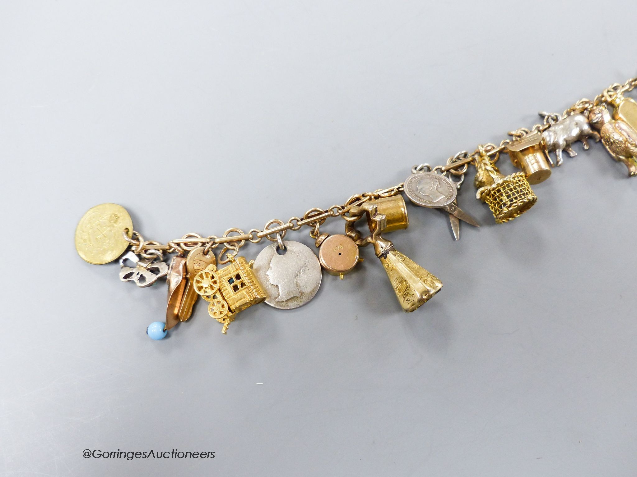A 9c charm bracelet, hung with nineteen assorted charms, gross 38 grams.